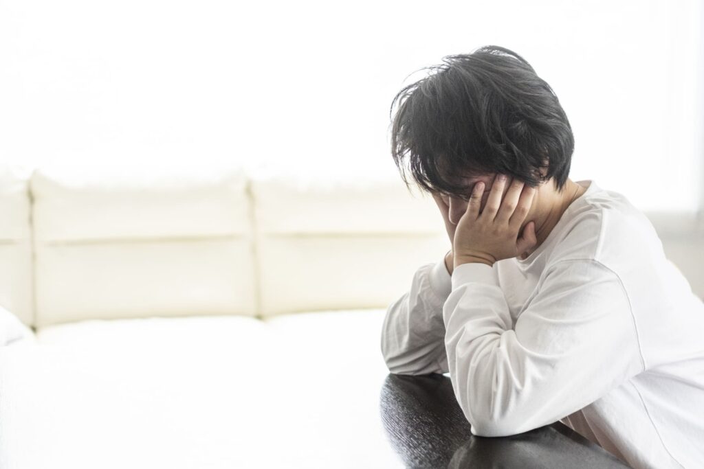 椅子に座って悩んでいる男性の写真