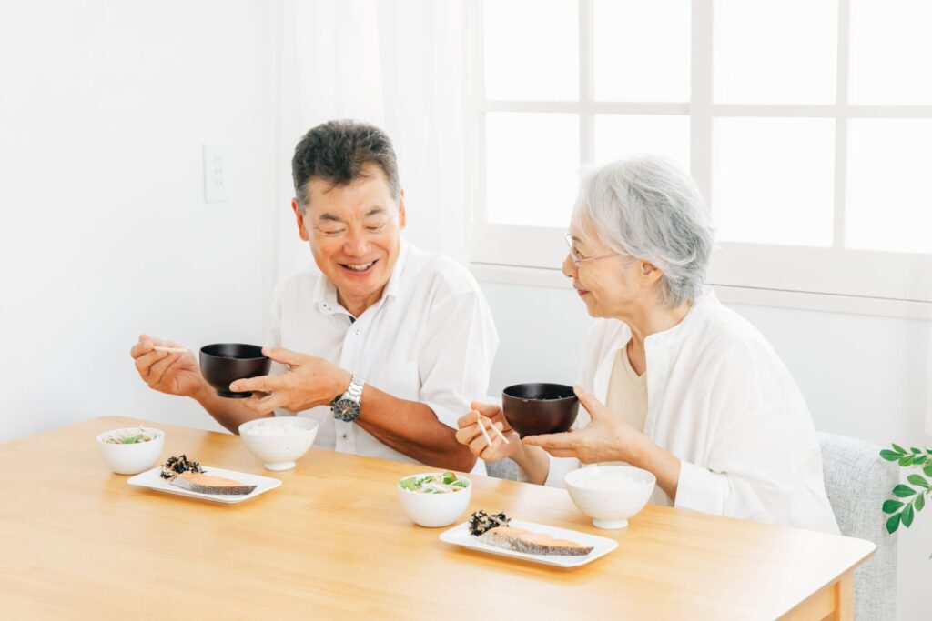 笑顔で食事を楽しむ高齢夫婦の写真