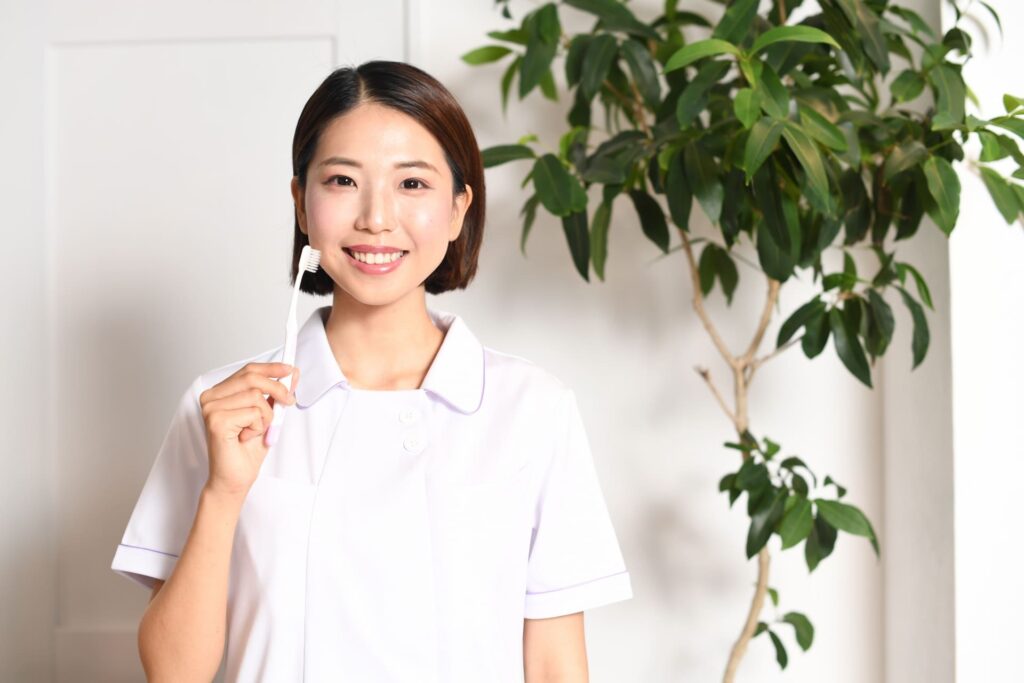 歯ブラシを持ってブラッシング方法を説明する女性歯科医師の写真