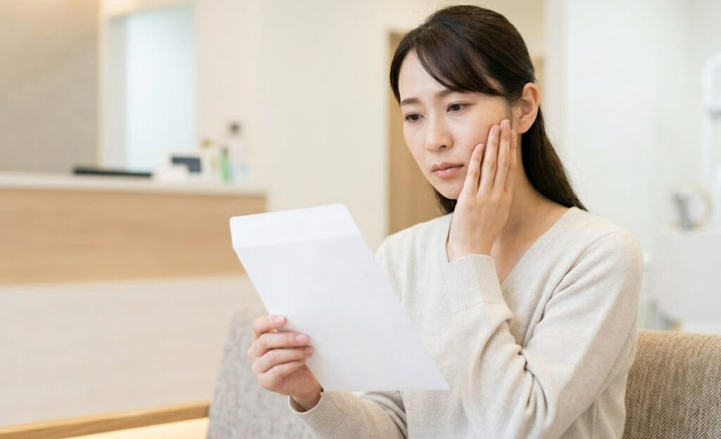 紹介状を手に、少し不安げに頬に手を添える日本人女性