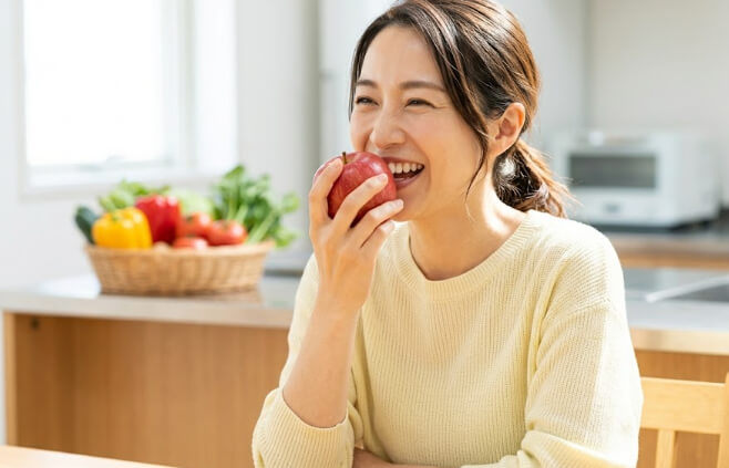 リンゴをしっかり噛んで味わう日本人女性の自然な笑顔