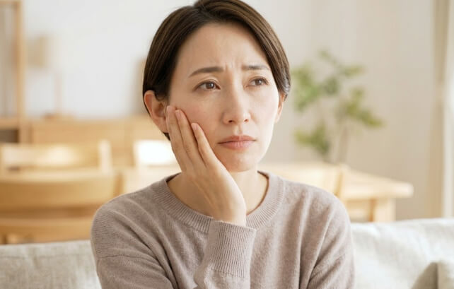 頬に手を添え、口元を気にする日本人女性