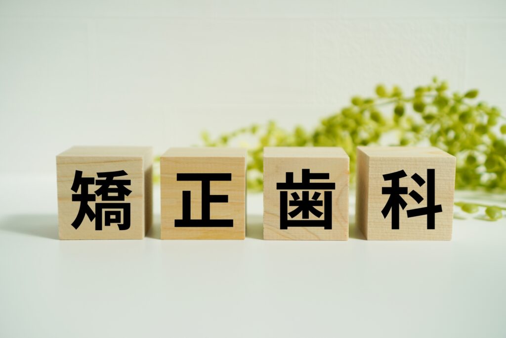 「矯正歯科」と書かれた木製ブロック。歯列矯正のイメージや治療案内を表す視覚素材に最適。