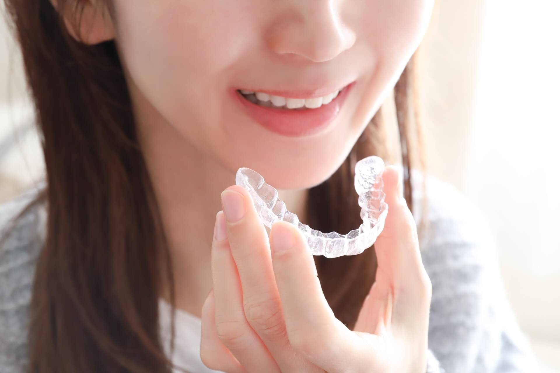 マウスピース矯正装置を手に持つ女性の様子