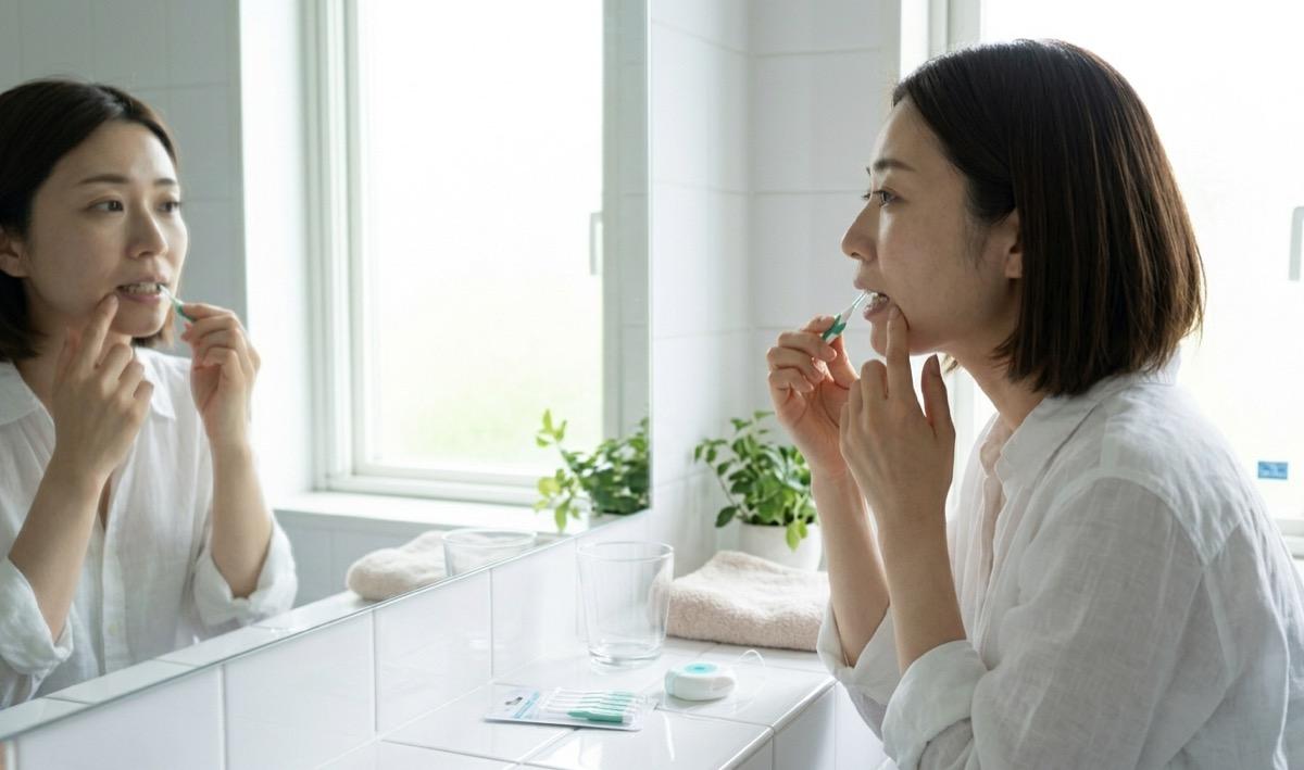 自宅でデンタルフロスを使い歯のお手入れをする女性の様子