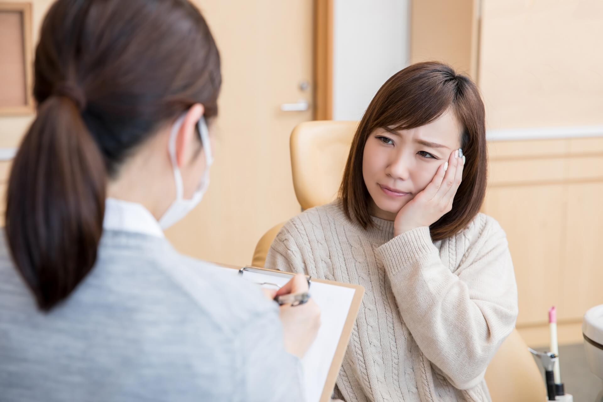 診察台に座り、歯の違和感や一時的な痛みの症状を医療従事者に伝える様子