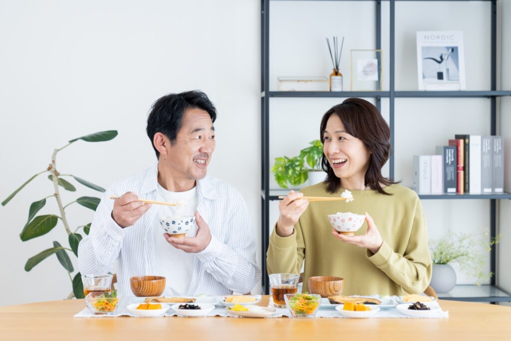 笑顔で食事や会話を楽しむ50代〜60代の夫婦