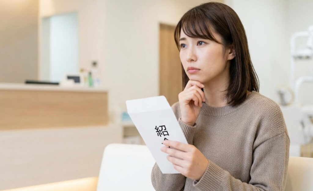 紹介状を手に、少し不安げに歯科医院の待合室に座る日本人女性
