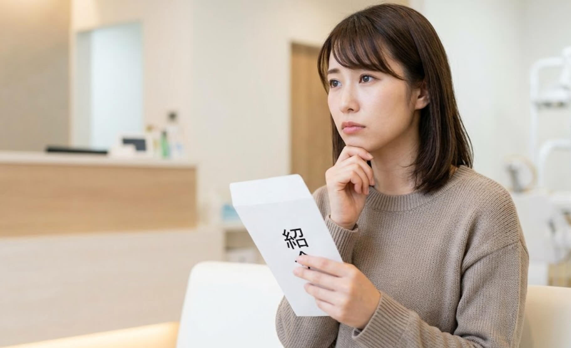 紹介状を手に、少し不安げに歯科医院の待合室に座る日本人女性