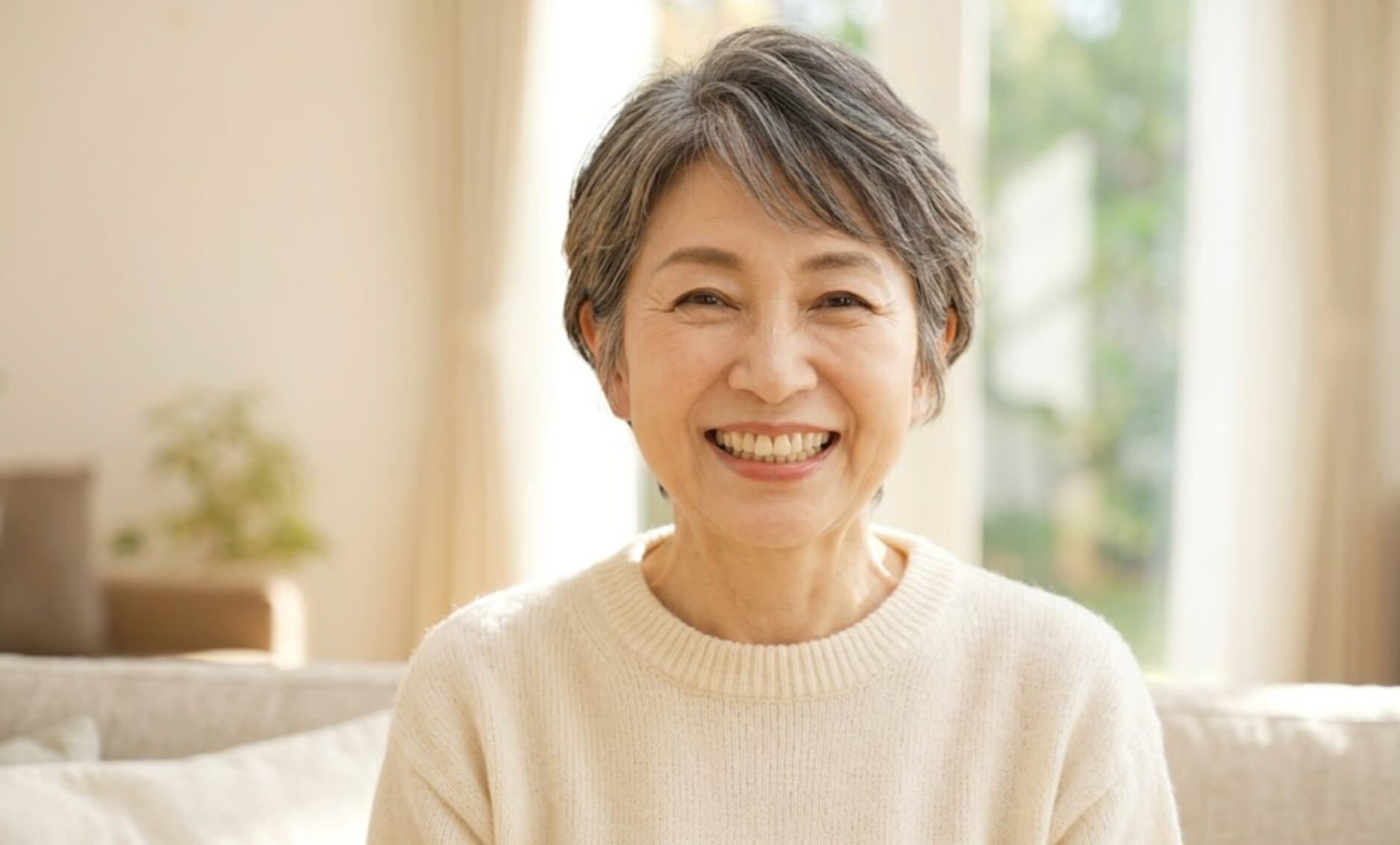 健康で美しい歯で、明るく笑う60代の日本人女性のバストアップ写真の様子。