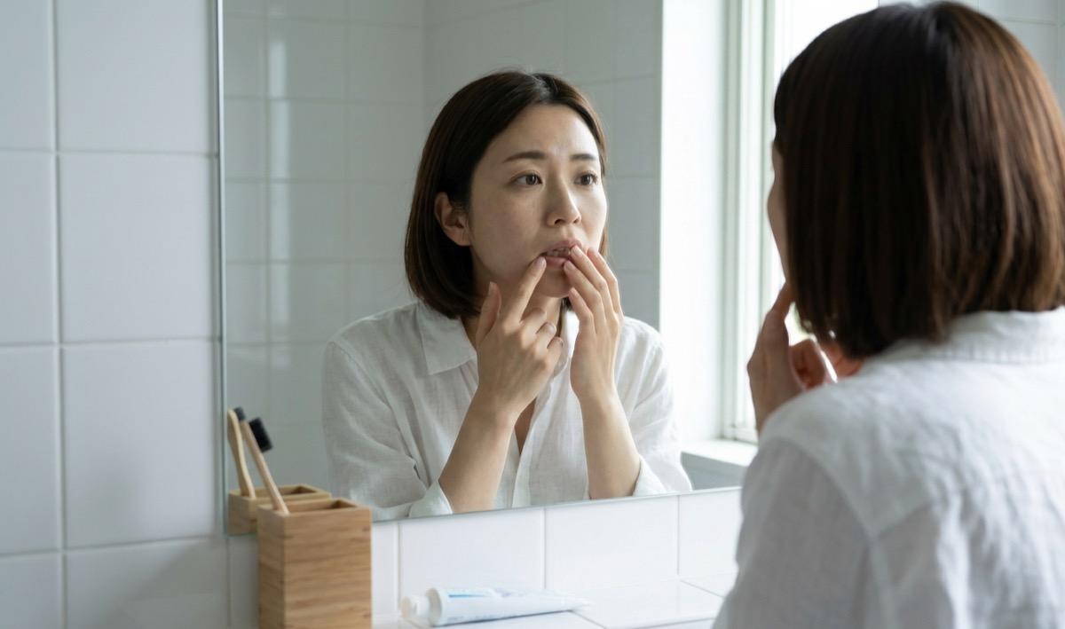 鏡の前で自分の歯ぐきの状態を気にしている女性の様子