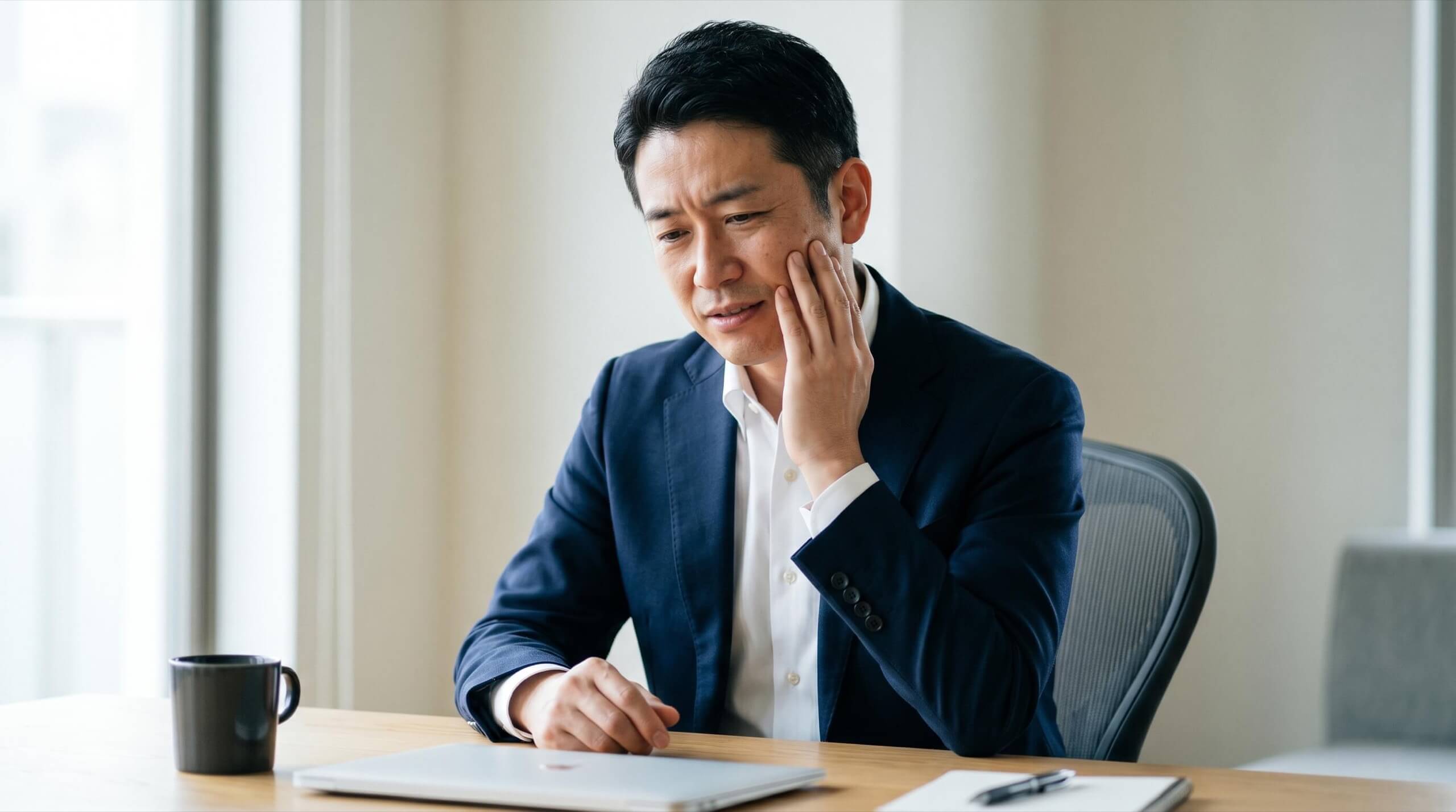歯の痛みで頬を押さえる男性の様子