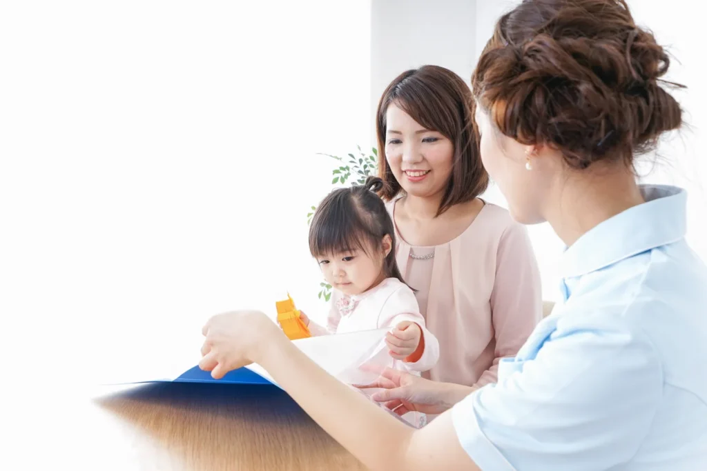 小児矯正の医療費控除の手続きを歯科スタッフに相談する母子