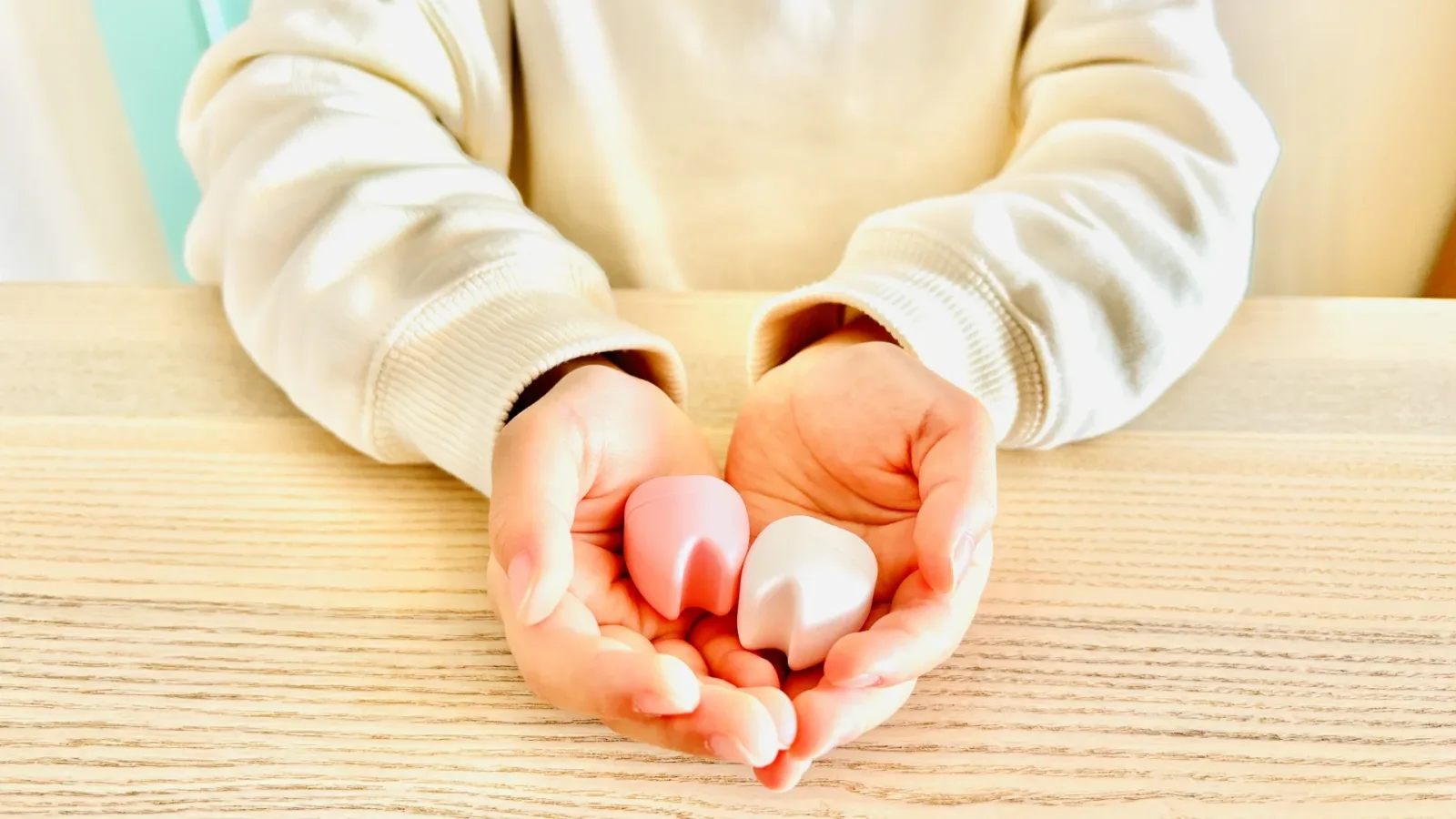 乳歯と永久歯の模型を両手にのせる子ども(小児矯正を第一期でやめる判断を解説する記事)