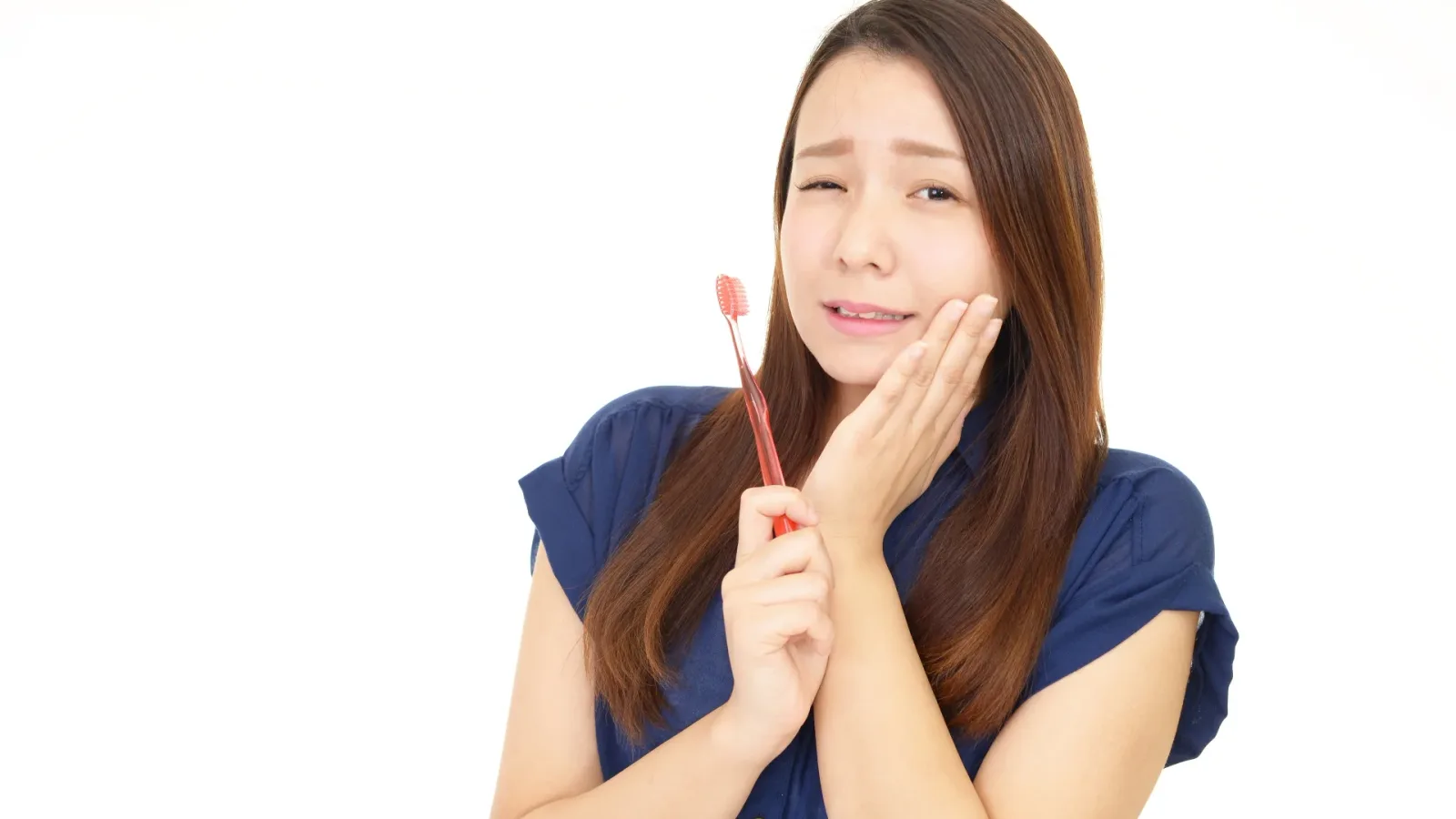 歯ブラシを手に頬を押さえて顔をしかめる女性(歯医者が怖くて行けない大人向けの記事)